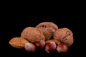 Walnuts, hazelnuts and almonds over a black background