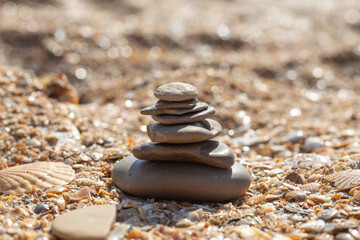 Fototapeta na wymiar Pyramid of stones laid out on a sandy beach, selective focus. Relaxation and balance