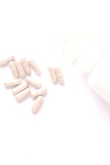 Gray pill capsules and pill bottles were placed on a white table.