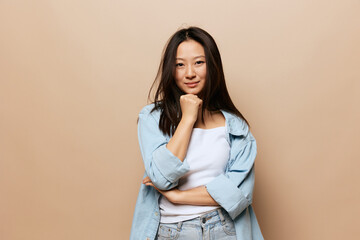 Cute smiling thoughtful tanned adorable young Asian lady reclines on hand fist posing isolated on beige pastel background. People and Emotions concept. Copy Space Offer Banner.