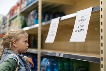 Little girl shopping and looking to empty shelves in a grocery store
