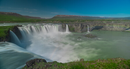 Fototapeta premium Long exposure photo of magnificent Godafoss waterfall in northern Iceland on a warm summer day. Visible frog from drops of water coming from the waterfall.