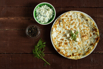 Flatbread with feta cheese, next to dill, lettuce, black pepper in bowls. Top view.