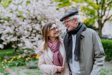 Happy senior man with adult daughter outdoors on a walk in park.