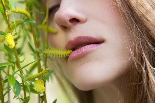 Close-up of a young woman against the background of birch catkins in a spring park.