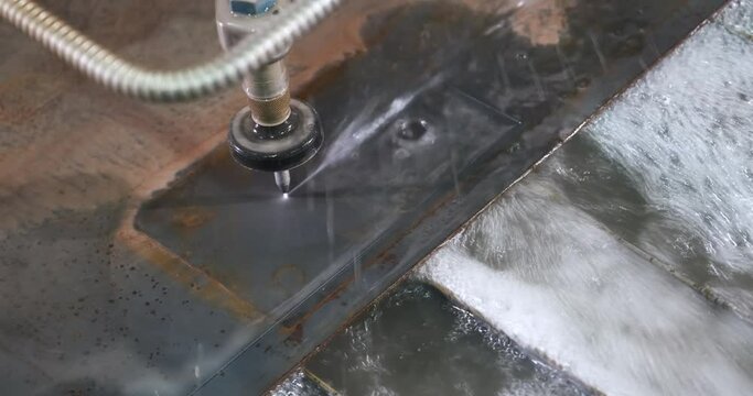 Waterjet CNC machine under pressure cutting elements out of metal sheet. Modern technologies in industries, manufacturing and metallurgy, close-up shot. Hydroabrasive system
