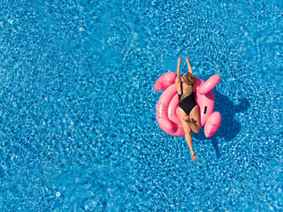woman on flamingo pool float in pool. Summer holidays
