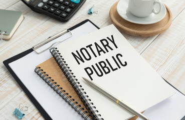 NOTARY PUBLIC is written in a white notepad near a calculator, coffee, glasses and a pen.