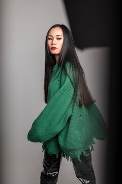Fashion Korean beauty woman with long hair in ripper stylish knitted green sweater and leather pants walks and poses in studio