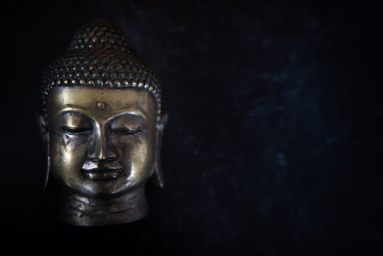 Buddha head on dark black simple background. Left image.