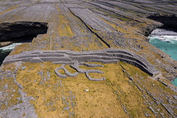 Remains of Black fort on Aran Island. Aerial drone view. County Galway, Ireland. Popular tourist landmark. Stone building on a rough rock terrain by the ocean.