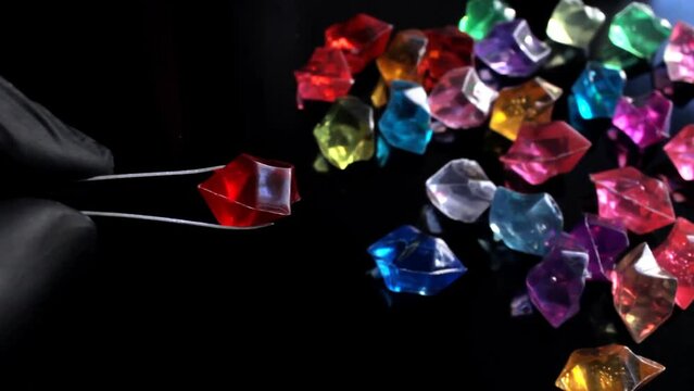 An appraiser in a pawnshop holds a red ruby-like gemstone with tweezers while examining it for fakes