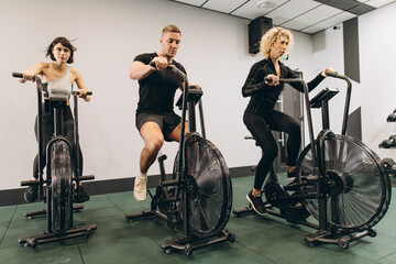 Young man and women using air bike for cardio workout at cross training gym