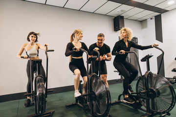 Fototapeta na wymiar Young women make exercising on air bikes at gym with trainer motivating.