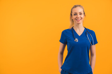 attractive blonde Caucasian nurse smiling on orange background copy space studio shot medium shot...