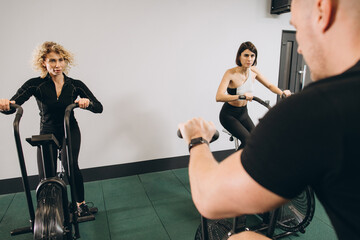 Young man and women using air bike for cardio workout at cross training gym