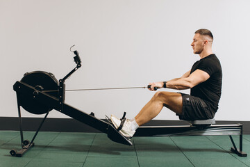 Man running rowing excercise in the gym - obrazy, fototapety, plakaty