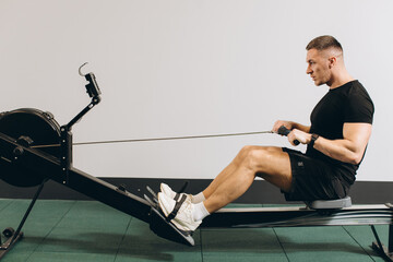 Man running rowing excercise in the gym - obrazy, fototapety, plakaty