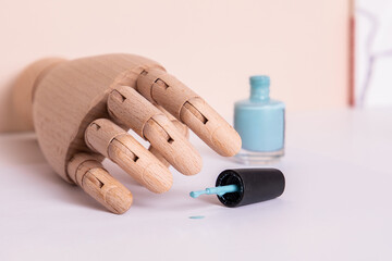Wooden hand near blue gel polish. Manicure and nail care concept.
