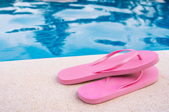 Close-up of pink flip flops for swimming pool or beach. Swimming pool water texture. Pool background with summer objects. to use text.