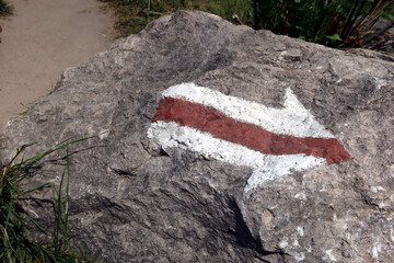 Stone with red trail sign. Arrow shaped trail sign showing the right direction 