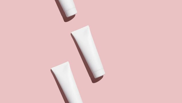 Pattern from mock up cosmetic or toothpaste tubes on pink background - Stop motion animation