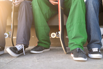 Detail of a group of young skaters sitting with their skateboards in a skate park - Extreme sport, friendship, youth concept - Selective Focus.