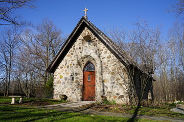 Historical old vintage abandoned mini stone church stands enclosed around a forest out in the...
