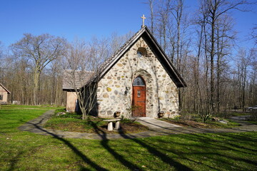 Historical old vintage abandoned mini stone church stands enclosed around a forest out in the countryside