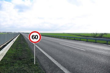 Traffic sign MAXIMUM SPEED 60 near empty asphalt road