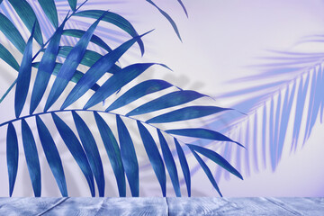 Blue palm branches and wooden table against light background. Summer party