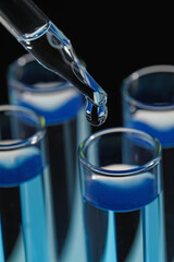 Dripping reagent into test tube on black background, closeup. Laboratory analysis