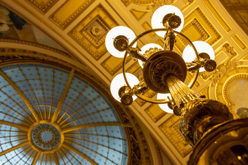 A decorative lantern lighting under a decorative ceiling with a cupola