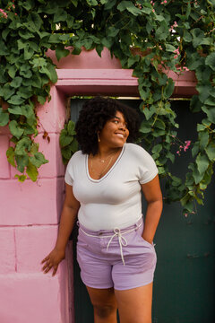 Portrait of a smiling woman standing by a pink wall