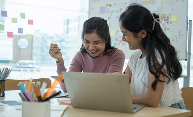 Friendly female colleagues discussing new project together in creative office.