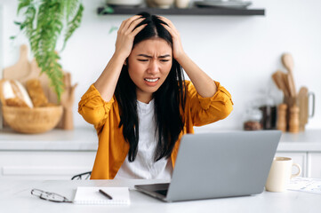 Frustrated sad puzzled Asian brunette girl, freelancer or designer, got a negative result, failed...
