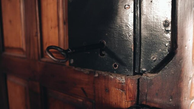 Mano de anciano abre puerta hist&oacute;rica. Orfebrer&iacute;a llave antigua. Elderly hand opening old door.