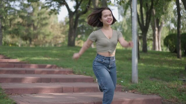 Carefree laughing little woman running downstairs in summer park laughing out loud. Positive joyful Caucasian person with dwarfism having fun on weekend outdoors leaving