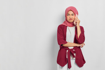 Annoyed beautiful Asian woman in casual shirt talking on mobile phone and looking away at copy space isolated over white background