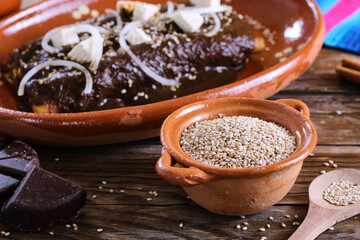 tortillas wrapped in mole poblano with sesame seeds, cheese and onion. enchilas poblanas, mexican food