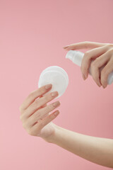 Topview of hand model using makeup remover on cotton pad in pink background for cosmetic advertising	