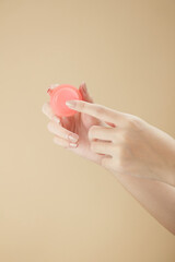  Top view of hand model using lipstick on hand in beige background for cosmetic advertising