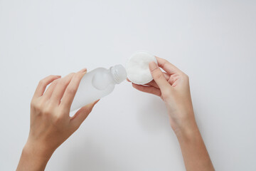 Topview of hand model using makeup remover on cotton pad in white background for cosmetic...