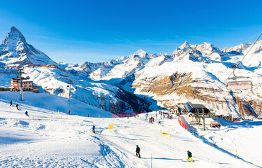 Scenic mountain landscape with high pyramidal rocky peak Matterhorn in Pennine Alps covered in snow on sunny winter day with modern ski lifts at its foot, Switzerland
