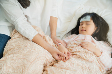 Sick little child with temperature in bed. Hand of mother on his forehead. photo of caring mother holding head on sick daughter forehead.