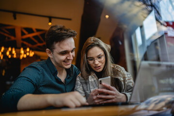 Two people young caucasian couple man and woman female and male friends or boyfriend and girlfriend taking selfie photos or making a video call while sitting at cafe copy space fun and romance