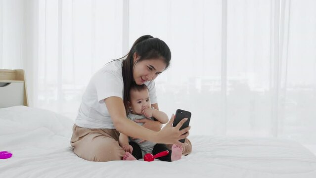 A single mother shows her baby girl to take photos with a smartphone 