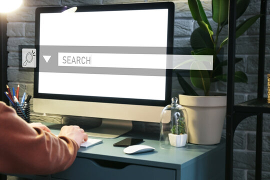 Woman using computer at table in evening. Concept of search