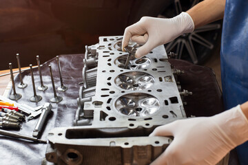 Auto mechanic working in garage. Repair service.  opened automobile engine cylinder head for...