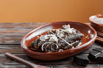  tortillas wrapped in mole poblano with sesame seeds, cheese and onion. enchilas poblanas, mexican food
